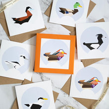 Load image into Gallery viewer, 6 Geometric duck designs on mall greetings cards. The center card is franed by a bright orange box. There are 6 additional cards that surround it.