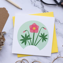 Load image into Gallery viewer, Small card with illustration of a Hellebore full flower with two buds and two leaves. The card is on top of a yellow envelope which is on top of a marble surface.