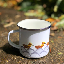 Load image into Gallery viewer, Ducks in a row - Enamel mug on ground with print of geometric duclings on water. They are facing away from the handle and following their mother who is out of sight on the reverse side of the mug.
