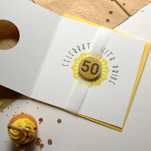 Load image into Gallery viewer, Greeting card with &#39;Celebrate with Pride&#39; design on a wooden surface with a cupcake.