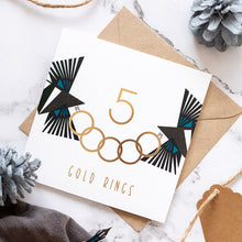 Load image into Gallery viewer, 5 gold rings card with foiled detail on the rings and text. There are two magpies holding the rings