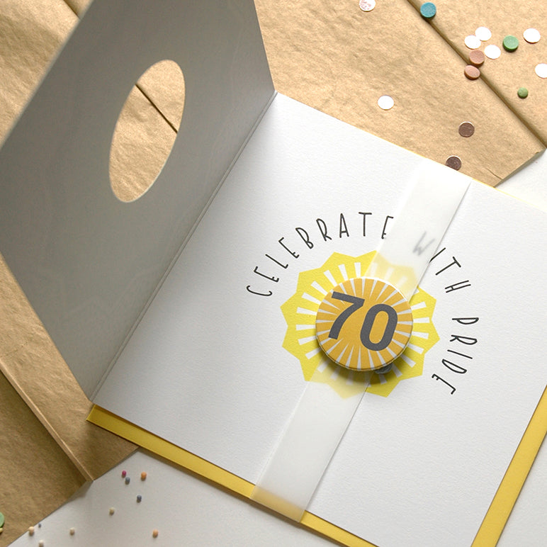 Open card with 'Celebrate with pride' text and decorative elements on a beige background.