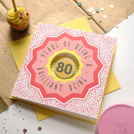 80th birthday card with decorative elements on a table with a cupcake.