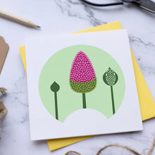 Load image into Gallery viewer, A square white art print card featuring a stylized pink and green floral design inside a light green circle, styled on a yellow envelope and marble surface with scissors, pencil, twine, and kraft labels.
