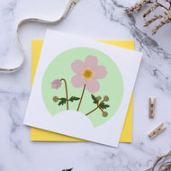 Card with floral design on a marble surface with a pen and twigs.