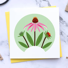 Load image into Gallery viewer, A square white greeting card with a colorful illustration of pink and red echinacea inside a light green circle, layered over a yellow envelope on a white marble surface with craft props.