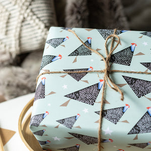 Gift box wrapped in paper with guineafowl bird pattern and tied with twine against a blurred background