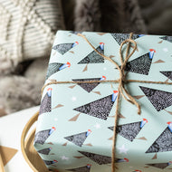 Gift box wrapped in paper with guineafowl bird pattern and tied with twine against a blurred background