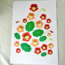 Load image into Gallery viewer, A botanical art print featuring red and peach flowers with green leaves on a white sheet of paper, laid flat on a light-colored fabric background.
