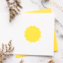 Load image into Gallery viewer, White card with yellow sun design on a marble surface with dried flowers.