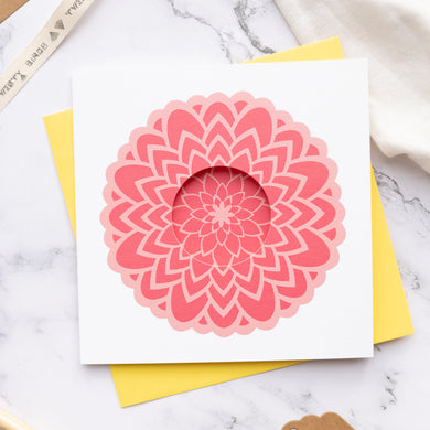 Card with pink floral design on a yellow envelope against a marble background