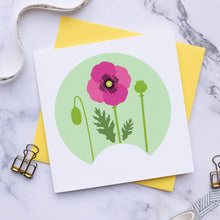 Load image into Gallery viewer, A square white art print card featuring a pink poppy flower and green leaves inside a light green circle, styled on a yellow envelope over a white marble background with ribbon, clips, and washi tape.