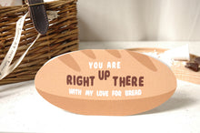 Load image into Gallery viewer, A novelty bread-shaped greetings card with the text 'YOU ARE RIGHT UP THERE WITH MY LOVE FOR BREAD' in brown and white lettering, styled on a white surface with a wicker basket in the background.