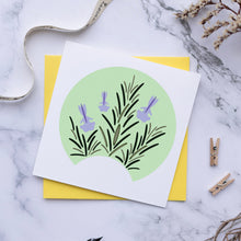 Load image into Gallery viewer, A square white art print card featuring a circular illustration of green rosemary leaves and purple flowers, layered over a yellow envelope on a white marble background with decorative dried flowers, a pen, and small wooden clothespins.