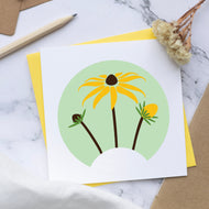 Card with Rudbeckia
 design on a marble surface with stationery items.