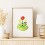 A framed art print featuring a colorful spring flower illustration on a white background, styled on a light wood shelf next to a white vase with dried grass, a small bowl, and a woven lamp.