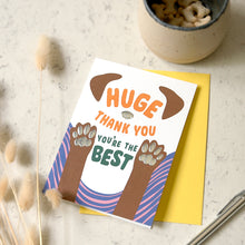 Load image into Gallery viewer, A dog-themed thank you card with a yellow envelope, styled on a light marble surface with dried bunny tail grass, a ceramic bowl of treats, and metal pen.