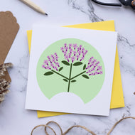 Card with floral design on a marble surface with scissors and twine.