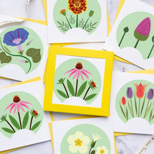 Load image into Gallery viewer, A styled flat-lay of multiple square floral art cards with white backgrounds and pale green circular flower illustrations, some layered over yellow envelopes. A ribbon is visible on a light marble surface.