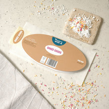Load image into Gallery viewer, The back of a die cut greetings card, shown on a light textured surface with scattered sprinkles and icing sugar. The card is on a bread bag envelope.